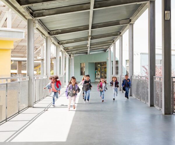 Young school kids running on a walkway in their school